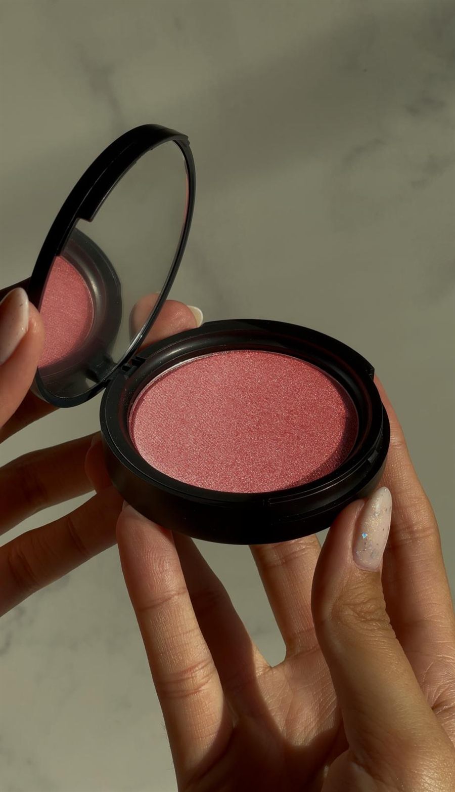 Mãos a mostrar um blush aberto, num vídeo UGC de maquilhagem